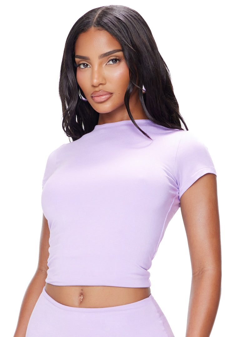 Woman wearing a light purple crop top on a white background