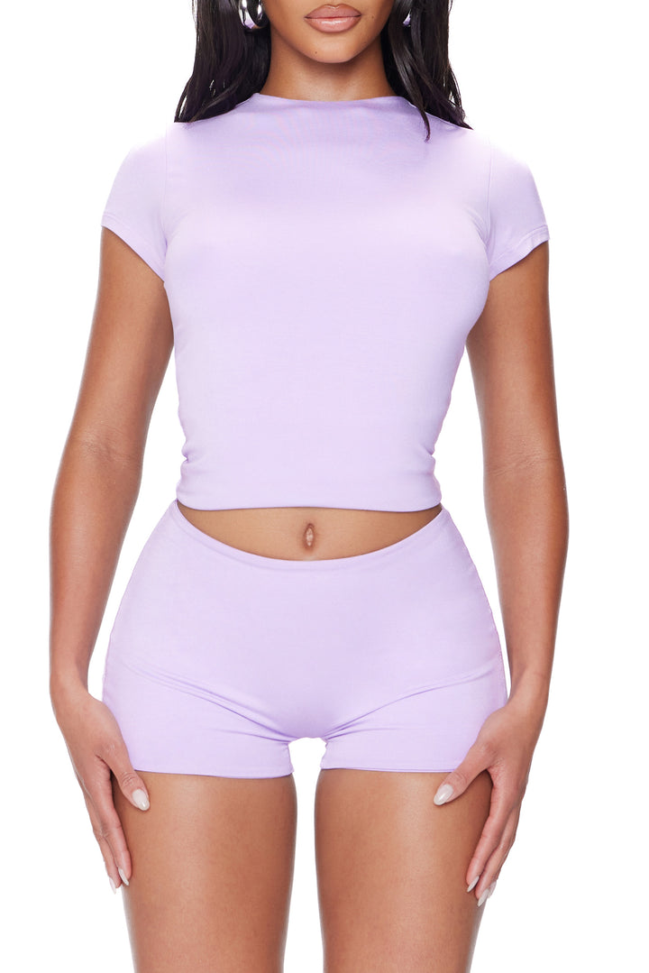 Person wearing a matching lavender crop top and shorts set on a white background