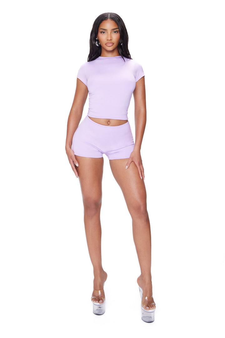 Woman wearing a matching lavender top and shorts set on a white background